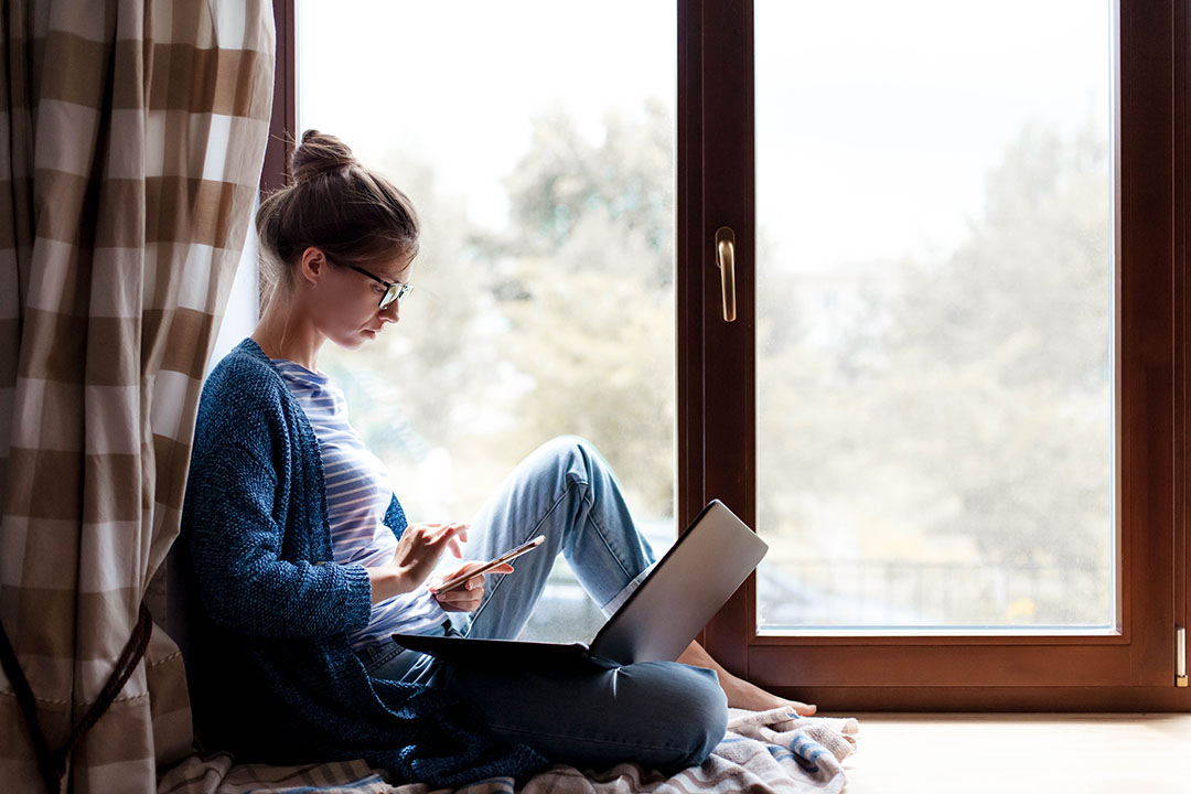 Working from home. Young woman using laptop, phone, Internet. Freelancer workplace